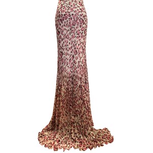 May include: A floor-length skirt with a pink and cream leopard print. The skirt has a high waist and a flowing, pleated design that flares out towards the bottom. The fabric appears lightweight and suitable for warmer weather.