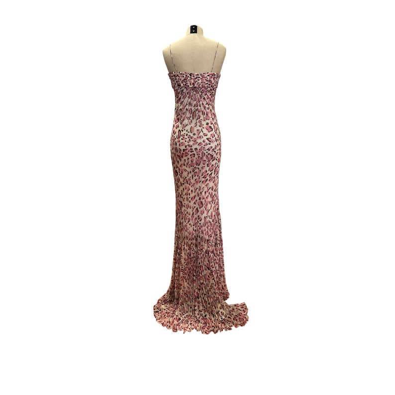 May include: A floor-length, strapless gown with a pink and cream leopard print. The dress features a fitted bodice and a flowing skirt that flares out at the bottom. The dress is displayed on a mannequin against a white background.