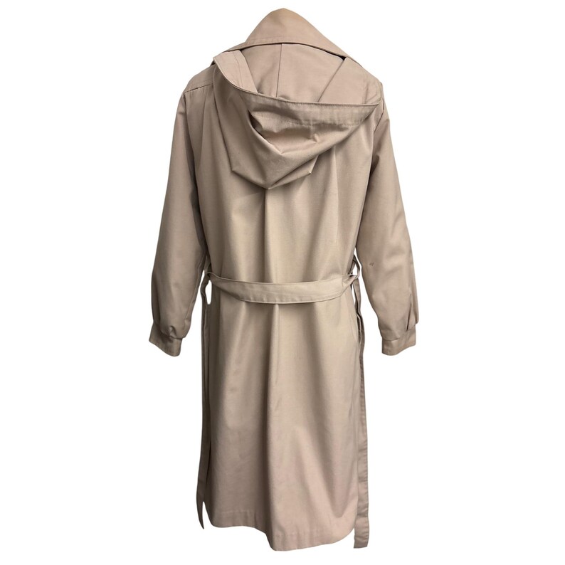 K&ouml;nnte beinhalten: Ein beigefarbener Trenchcoat mit Kapuze, langen &Auml;rmeln und einem G&uuml;rtel. Der Mantel ist aus einem glatten Stoff gefertigt und hat ein klassisches Design. Der Mantel ist neutralfarben und kann in verschiedenen Umgebungen getragen werden.