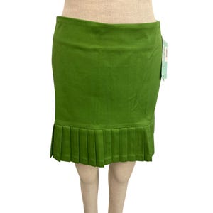 May include: A bright green skirt with a pleated hem. The skirt is a solid color and appears to be made of a smooth fabric. A tag is attached to the side.