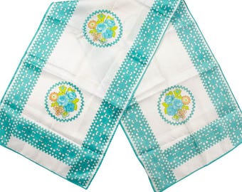 May include: White rectangular table runner with a teal border and floral design. The runner features a repeating pattern of teal hearts along the edges and circular floral arrangements with blue and orange flowers.