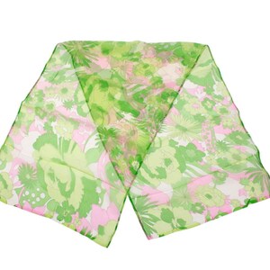 Pode incluir: Um lenço transparente com um padrão floral em tons de verde, rosa e branco. O lenço é retangular e parece ser feito de um tecido leve. O design floral inclui várias formas de flores e padrões de folhas.