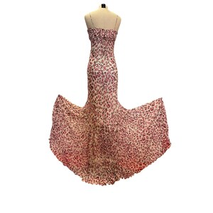 May include: A strapless, floor-length gown with a pink and white leopard print. The dress is displayed on a mannequin, showcasing its fitted bodice and flowing, flared skirt. The fabric appears lightweight and delicate.