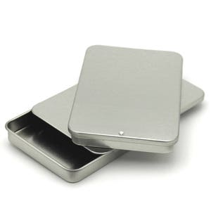 May include: A silver metal rectangular box with a lid. The box is open and the lid is sitting on top of the box.