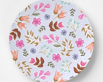 May include: A light blue ceramic plate with a floral pattern. The pattern features pink, orange, and purple flowers with brown stems and leaves.
