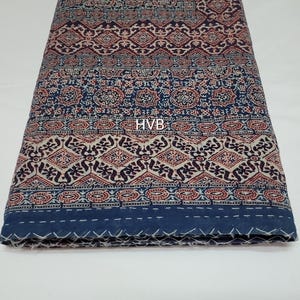 May include: A blue and white cotton fabric with a traditional Indian block print design. The fabric has a geometric pattern with red and brown accents. The fabric is folded in half and the edges are visible.