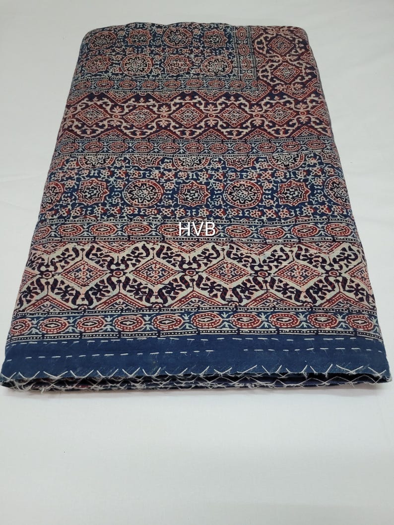 May include: A blue and white cotton fabric with a traditional Indian block print design. The fabric has a geometric pattern with red and brown accents. The fabric is folded in half and the edges are visible.