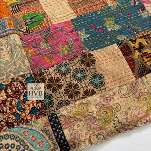 May include: A patchwork textile featuring a variety of patterned squares in shades of pink, blue, orange, and beige. The squares are stitched together with white thread. The textile has a floral and paisley design. The logo "HVB HVBCRAFTS" is visible.