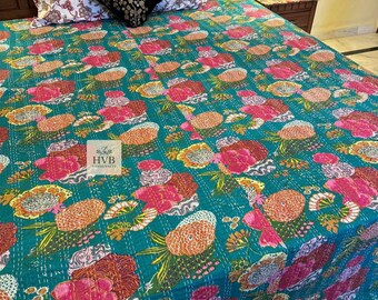May include: A teal kantha quilt with a floral pattern in shades of pink, orange, yellow, and green. The quilt is made of cotton and has a hand-stitched design. The quilt is shown on a bed with white and floral patterned pillowcases.