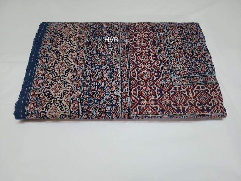May include: A blue and red patterned cotton quilt with the text "HVB" in the centre.