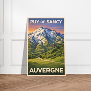 May include: A framed travel poster featuring the text "PUY DE SANCY AUVERGNE". The poster depicts a mountain range with snow-capped peaks, green hills, and a red cable car. The sky transitions from orange to blue.