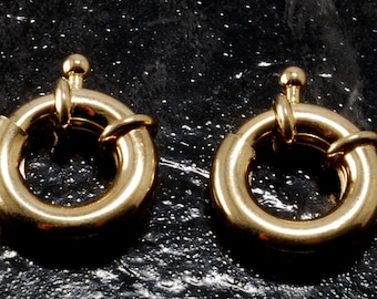 Op de afbeelding: Twee gouden metalen ringgespen met een gladde, gepolijste afwerking. De gespen zijn ontworpen om te worden gebruikt als sluiting voor kettingen, armbanden of andere sieraden.