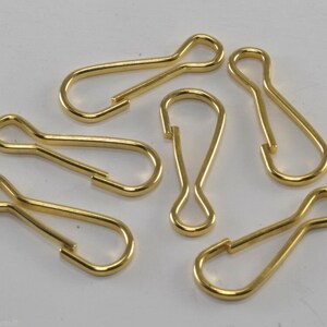 May include: Six gold-coloured metal key rings with a swivel clasp. The key rings are all the same size and shape.
