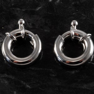 May include: Two silver-toned metal ring clasps with a small ball on the top of each clasp.