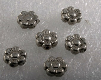 May include: Six silver flower-shaped beads with a hole in the center. The beads are about 1/2 inch in diameter.