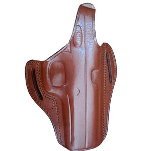 Op de afbeelding: Een bruine lederen holster met een gevormde vorm voor een vuurwapen, versterkte stiksels langs de randen en twee verticale riemsleuven aan de zijkanten voor bevestiging. Het oppervlak heeft een gladde, gepolijste afwerking met contouren.