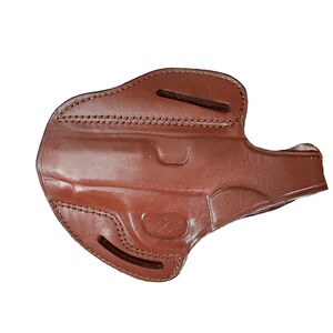Op de afbeelding: Een bruine lederen holster met een gevormde uitsparing voor een vuurwapen, versterkte stiksels langs de randen en twee horizontale riemsleuven aan de boven- en onderkant voor bevestiging. Het oppervlak heeft een gladde, gepolijste afwerking.