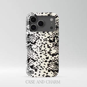 May include: A smartphone case with a black and white snakeskin pattern. The case has a glossy finish and features the text "CASE AND CHARM" at the bottom. The case is designed to fit a modern smartphone with multiple camera lenses.
