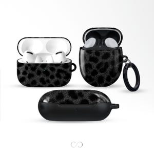 May include: Black leopard print AirPod cases in three different views. The cases are open and closed, showcasing the design. The cases have a black background with a black leopard print pattern. The cases are designed to protect and carry wireless earbuds.
