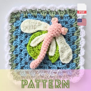 以下が含まれることがあります： 正方形のデザインの、かぎ針編みのトンボのパターン。 トンボはピンク、白、緑で、青と緑の背景です。 画像には「Crochet PATTERN」というテキストが表示されています。