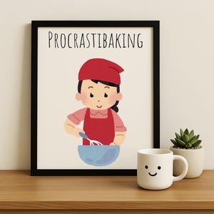 May include: A black framed print with the text "PROCRASTIBAKING" in white. The print features a cartoon illustration of a person wearing a red hat and apron, holding a whisk over a bowl.