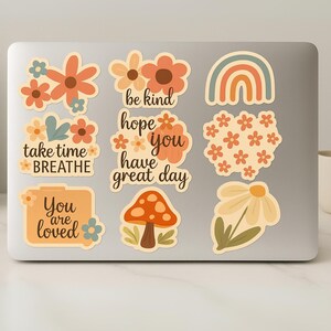 May include: A collection of colorful stickers with floral and nature-inspired designs. The stickers include a rainbow, mushroom, and flowers, along with positive affirmations like "You are loved" and "Take time to breathe."