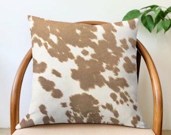 May include: A brown and white cowhide patterned throw pillow on a wooden chair.