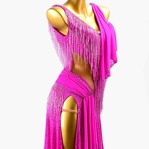 Puede incluir: Un vibrante vestido de baile fucsia con dise&ntilde;o de un solo hombro y abertura alta. El vestido presenta intrincados abalorios y largos flecos. El vestido se exhibe en un maniqu&iacute;.