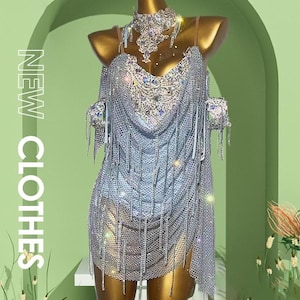 May include: A silver, beaded dress with fringe and a matching choker necklace is displayed on a mannequin. The dress has a plunging neckline and is embellished with sparkling rhinestones. The words "NEW CLOTHES" are printed vertically on the left side.