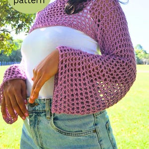 May include: A light purple, open-weave crochet shrug with bell sleeves. The shrug is worn over a white top and paired with blue jeans. The image includes the text "PDF crochet pattern" in a green circle.
