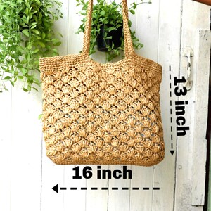K&ouml;nnte beinhalten: Eine gro&szlig;e, beige, geh&auml;kelte Tragetasche mit einer Breite von 16 Zoll und einer H&ouml;he von 13 Zoll. Die Tasche ist aus Naturfaser und hat eine gewebte Textur.