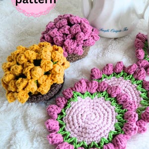 May include: A PDF pattern for crochet items including two textured flower-shaped bowls in yellow and pink, and two flat circular coasters with pink centres and green and pink floral borders, displayed near a white teapot with a gold knob.