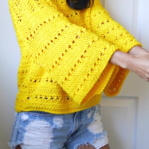 May include: A yellow crochet top with a loose fit and bell sleeves. The top has a delicate open stitch pattern.
