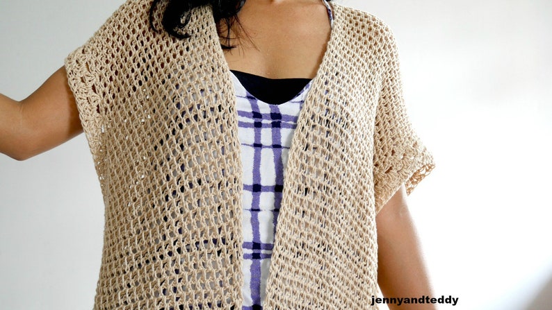 May include: A beige crochet cardigan with a loose, open-weave pattern. The cardigan has short sleeves and a V-neck.