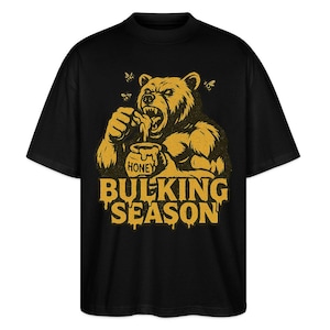 Peut inclure: T-shirt noir avec une illustration de dessin animé d'un ours mangeant du miel dans un pot. Le texte "Bulking Season" est écrit en jaune sous l'ours.