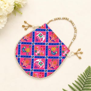 May include: A pink patterned pouch with a beaded handle and gold accents. The pouch features a repeating design of elephants and geometric shapes in white, blue, and yellow. The edges are trimmed with small white beads.
