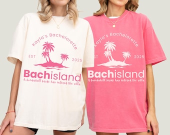 May include: Two oversized t-shirts, one cream and one pink, feature the text "Kayla's Bachelorette" with a palm tree graphic and "Bachisland" in pink. The shirts also include the text "A bombshell bride has entered the villa."