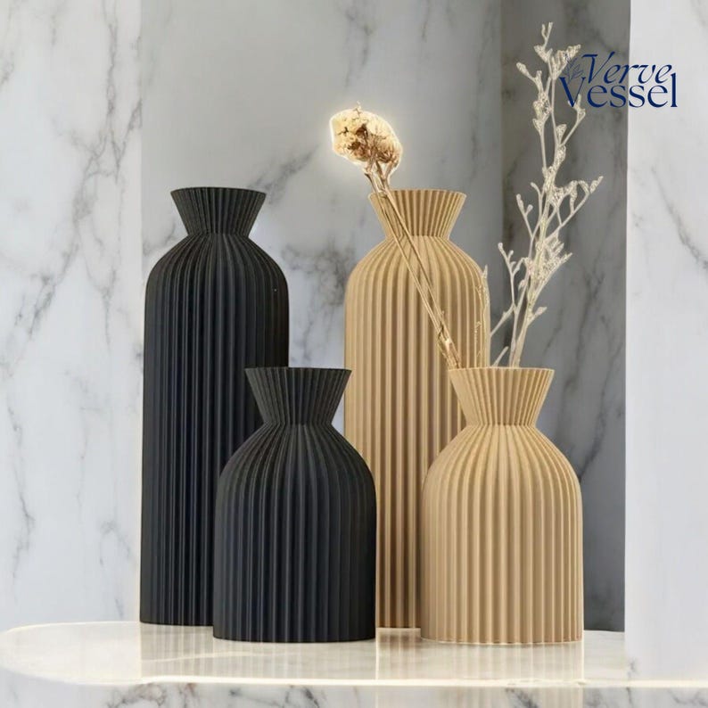 May include: Four decorative vases with a pleated design. Two vases are black and two are beige. The vases are arranged on a white surface. The text "Verve Vessel" is visible in the top right corner of the image.