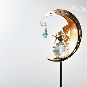 Solar moon fairy garden light with crackle glass globe and warm LED glow, eco-friendly outdoor stake lamp powered by solar panel, durable iron frame with waterproof IP65 design, 800mAh rechargeable battery for 10–12 hours of light, height 84 cm and width 16 cm, perfect for garden pathways, patios, balconies, or yard decoration, whimsical moon fairy design adds charm to outdoor spaces, energy-saving solar garden decor, great gift for garden lovers, birthdays, or housewarmings.