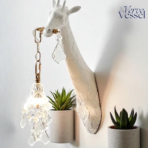 Puede incluir: Una taza de cerámica blanca con un asa negra y el texto "But First, Coffee" en negrita negra. La taza está llena de un líquido oscuro, probablemente café, y se encuentra sobre una superficie clara.