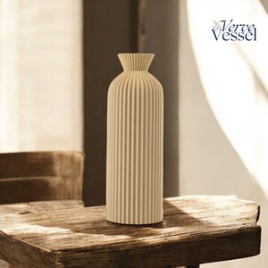 May include: A cream-coloured ceramic vase with vertical ridges. The vase is sitting on a wooden table.