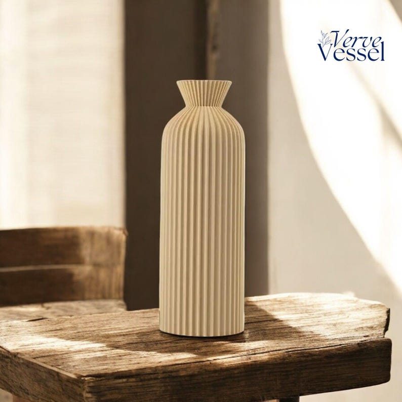 May include: A cream-coloured ceramic vase with vertical ridges. The vase is sitting on a wooden table.