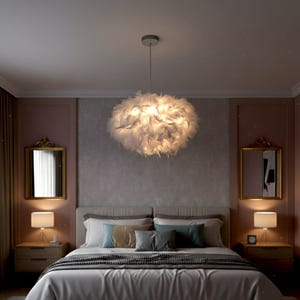 Könnte beinhalten: Schlafzimmer-Interieur mit einer großen, wolkenartigen weißen Feder-Hängeleuchte über einem Bett. Das Bett ist mit weißer Bettwäsche und dekorativen Kissen ausgestattet. Goldgerahmte Spiegel und Nachttischlampen tragen zum Ambiente des Raumes bei.