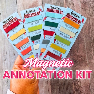 May include: A hand holds several light blue magnetic annotation kits. Each kit has a title, and colorful labels with text like "WTF?", "Fear Factor", and "Reactions". The kits are designed for annotating books.