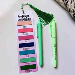 May include: A bookmark with a green tassel, a green pen, and a light green marker. The bookmark is labeled "Romance Annotation Key" and has color-coded sections for "Love," "Quotes," "Plot," "Characters," "Sad," "Angry," and "Additional."