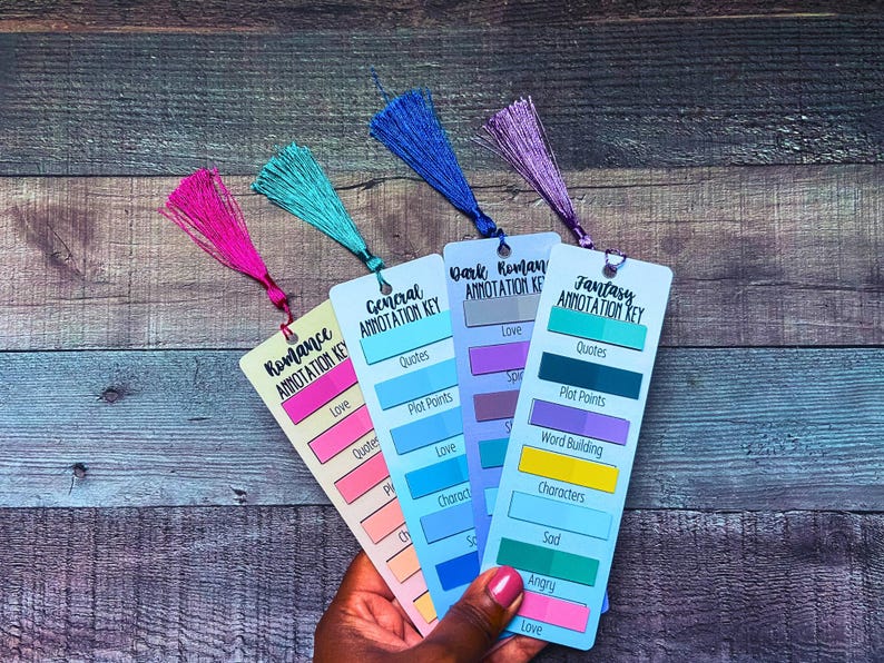 May include: Four rectangular bookmarks with annotation keys for Romance, General, Dark Romance, and Fantasy. Each bookmark features a colored tassel and printed labels for categories like Love, Quotes, and Plot Points with corresponding color-coded blocks.