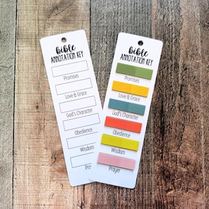 May include: Two white rectangular bookmarks labeled Bible Annotation Key with black text. One bookmark is blank, while the other features six colorful adhesive tabs aligned with categories including Promises, Love & Grace, God's Character, Obedience, Wisdom, and Prayer.