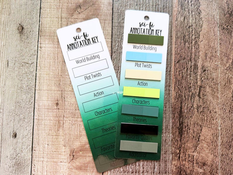 May include: Two rectangular bookmarks with a green gradient background and the text "sci-fi ANNOTATION KEY" at the top. One bookmark features blank white rectangles for notes, while the other has colorful adhesive tabs labeled World Building, Plot Twists, Action, Characters, Theories, Favorite Quotes, and Additional.