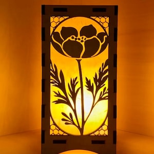 May include: A wooden lampshade with a cutout design of a flower and leaves. The lampshade is illuminated from within, casting a warm glow.