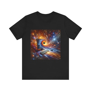 May include: Black t-shirt featuring a vibrant graphic of a computer monitor, keyboard, and mouse set against a swirling cosmic background with a black hole. The design incorporates shades of orange, blue, and yellow.